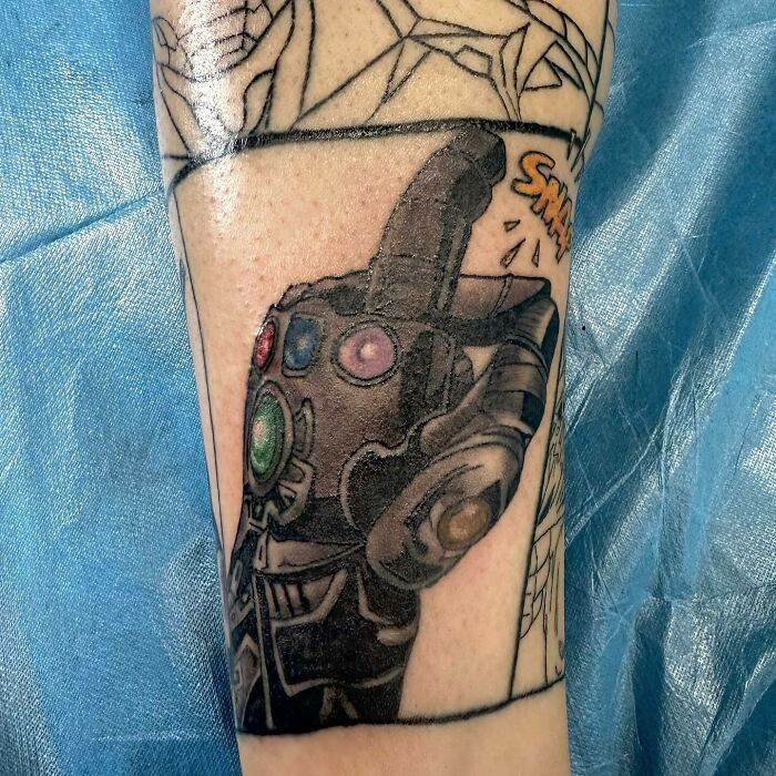 Marvel tattoo featuring the Infinity Gauntlet with colorful stones on an arm, inspired by comic book style.