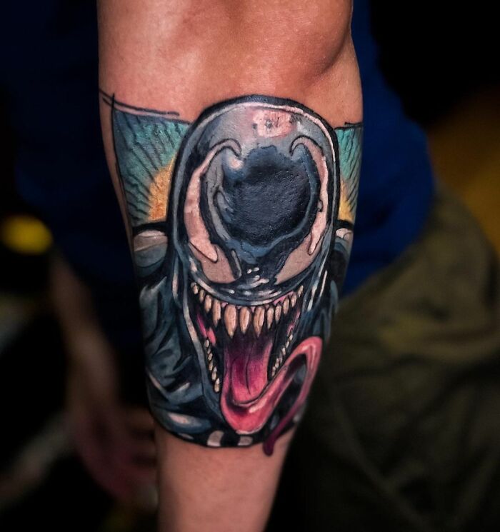 Arm displaying a detailed Marvel tattoo of Venom with vivid colors and sharp details.