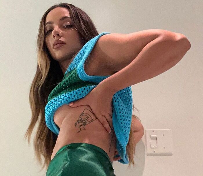 Person showing off a side tattoo featuring a line drawing design, wearing a colorful crochet top.