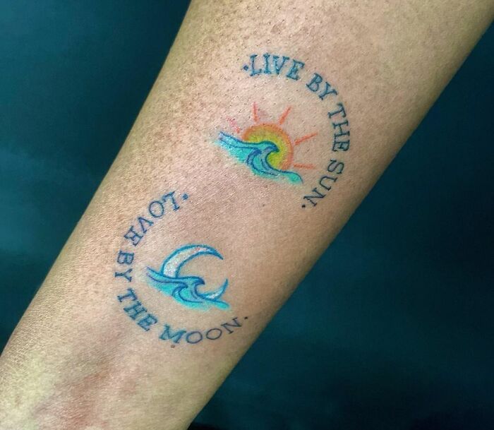 Colorful word tattoo with "Live by the Sun" and "Love by the Moon" design on the arm.
