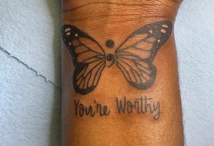 Butterfly tattoo with a semicolon and the words "You're Worthy" on forearm. Perfect word tattoo idea for new ink.