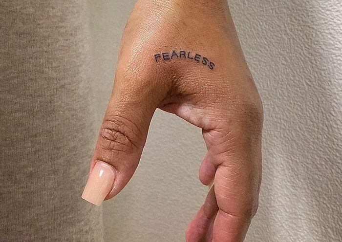 Hand with "Fearless" word tattoo on the side, showcasing one of the popular word tattoo ideas.
