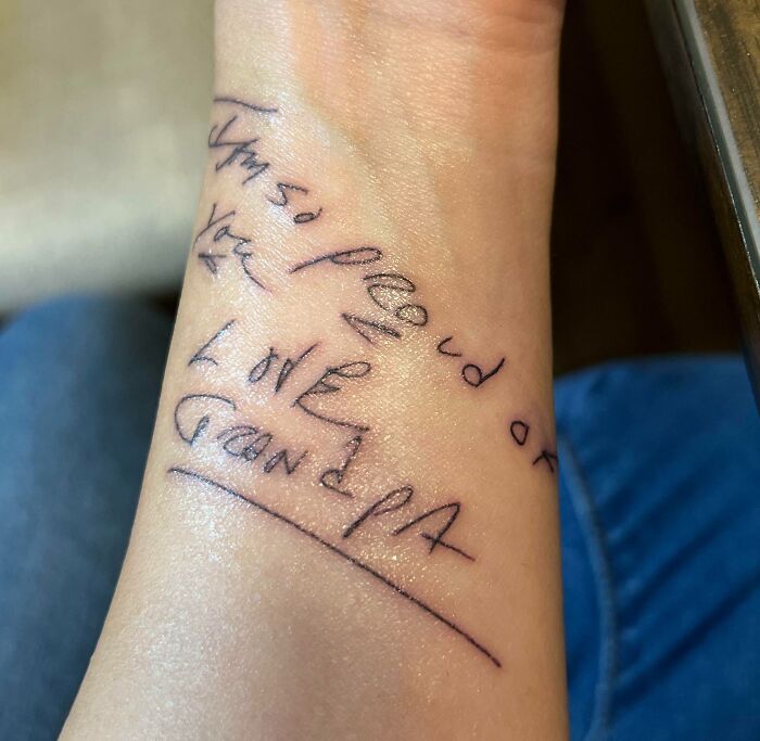 Handwritten word tattoo on wrist saying, "I'm so proud of you. Love, Grandpa."