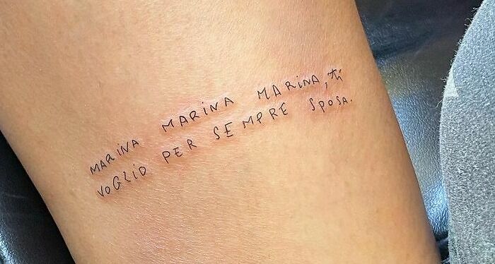 Word tattoo on forearm reading "Marina, Marina, Marina, ti voglio per sempre sposa" in minimalist font.