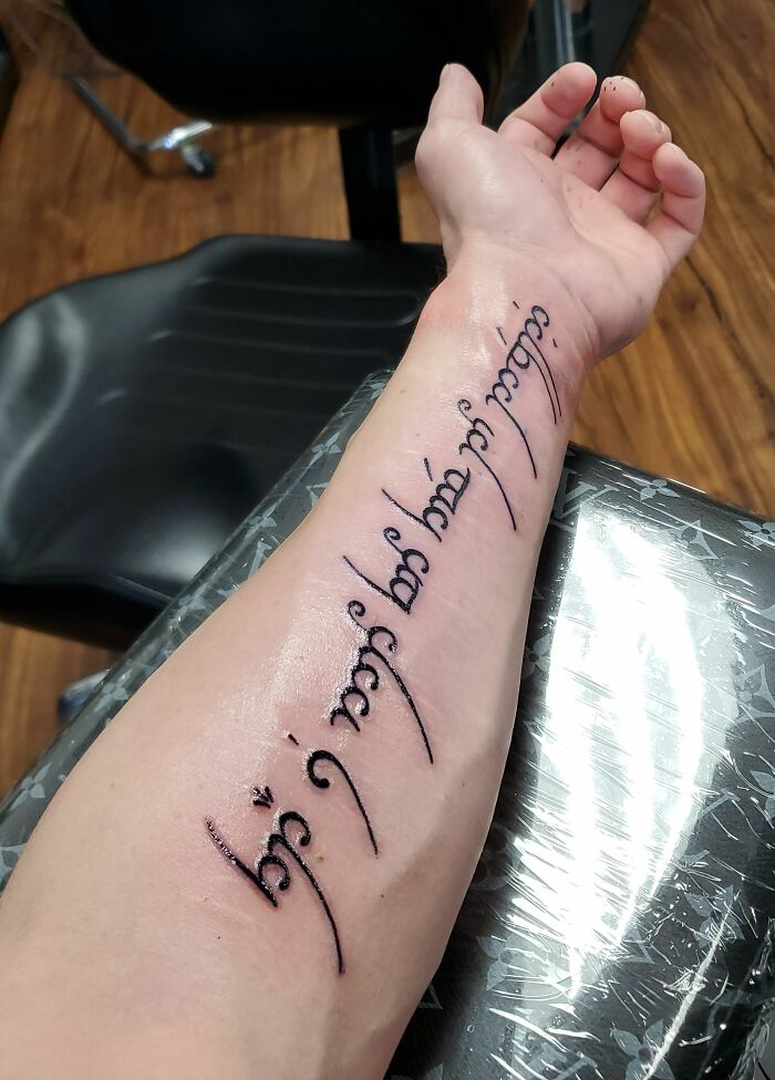A unique word tattoo on a forearm in elegant script style.