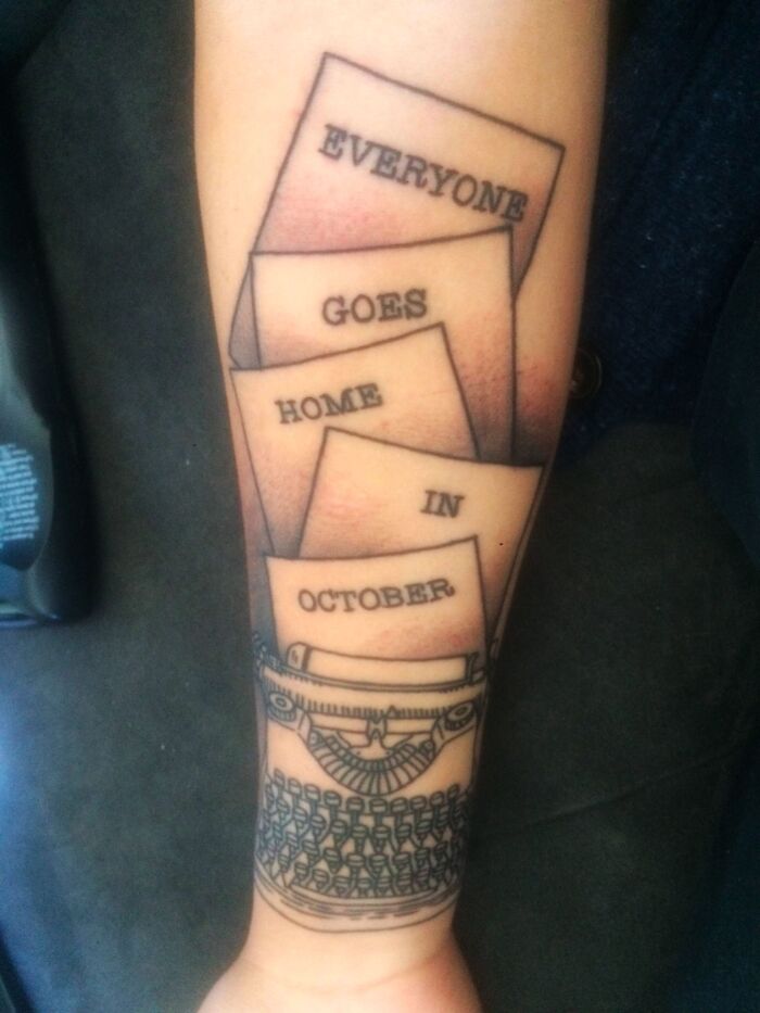 Typewriter tattoo with papers reading "Everyone goes home in October" as a unique word tattoo idea.