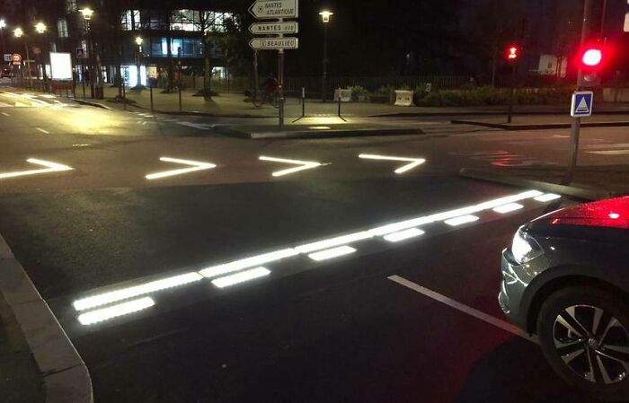 Illuminated crosswalk gadget at night in a city intersection.