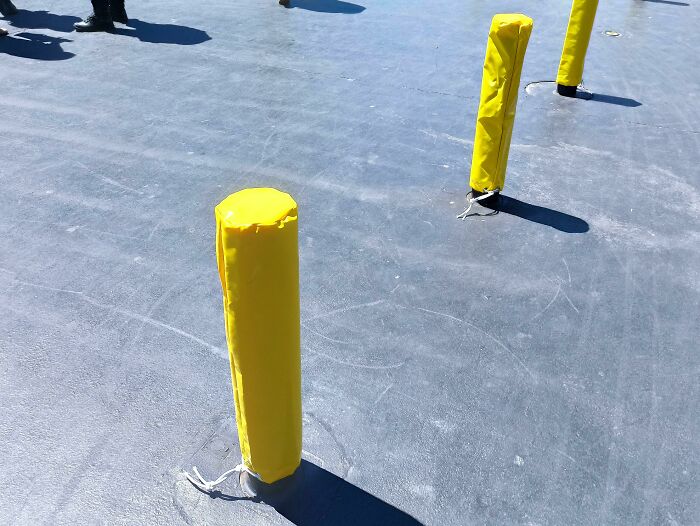 Yellow padded posts on a paved area, an interesting gadget highlighting safety in urban environments.