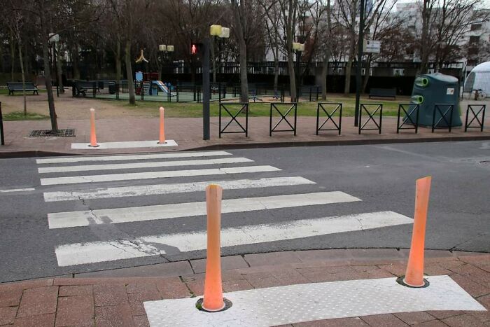 Crosswalk with innovative glowing posts in an urban park setting, showcasing interesting gadgets from cities worldwide.