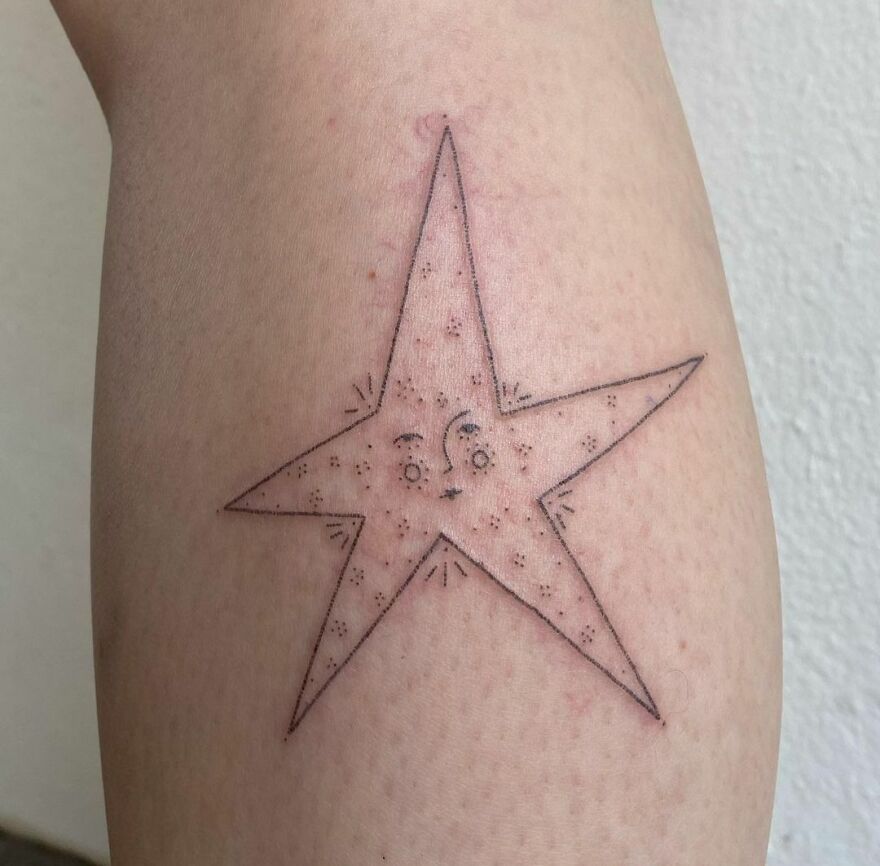 Minimalist space tattoo of a star with a face on an arm, showcasing outer space cool with delicate line work.
