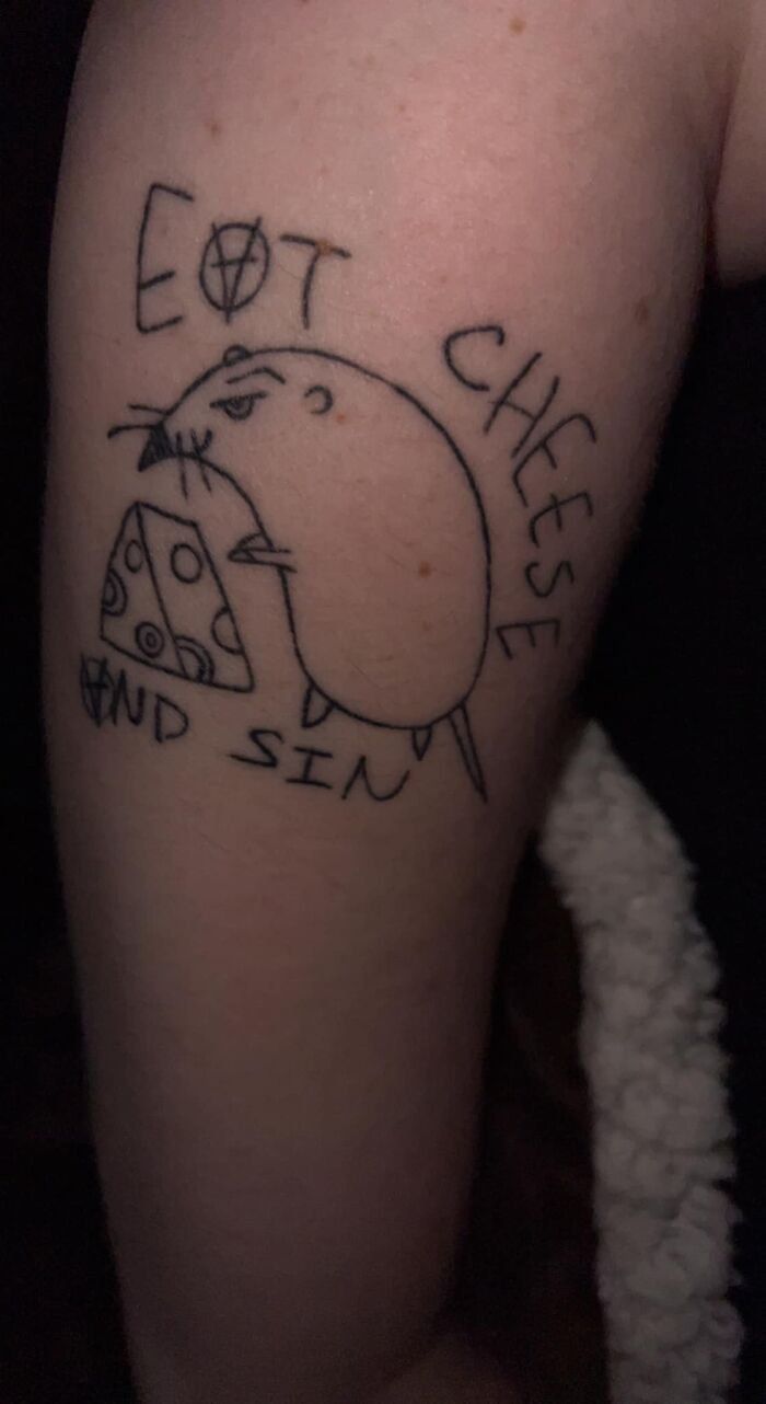 Tattoo of a poorly drawn rat eating cheese, text reads "EAT CHEESE AND SIN"; an example of permanent mistakes.