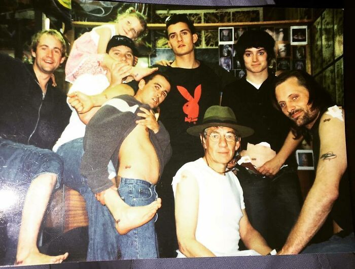 Group of people displaying tattoos in a casual setting, surrounded by tattoo-themed decor.