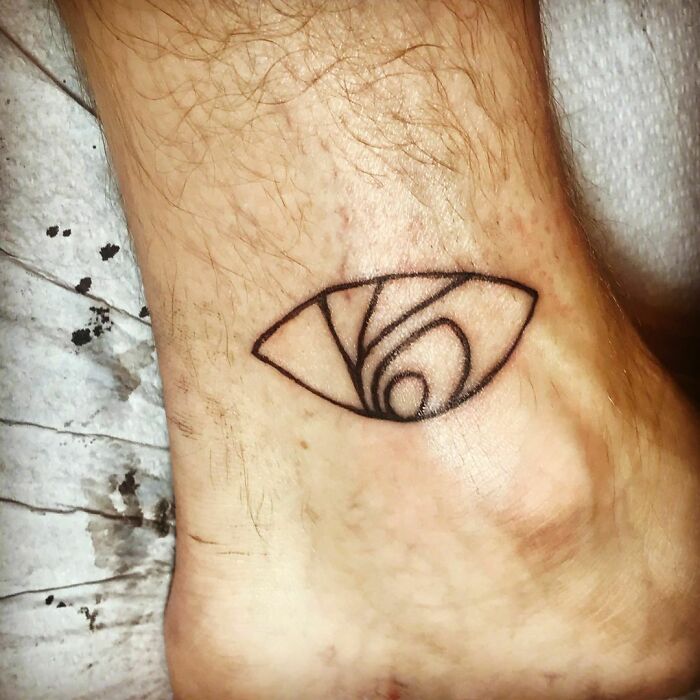 Abstract eye tattoo on ankle, inspired by celebrity tattoos, with intricate line detail.