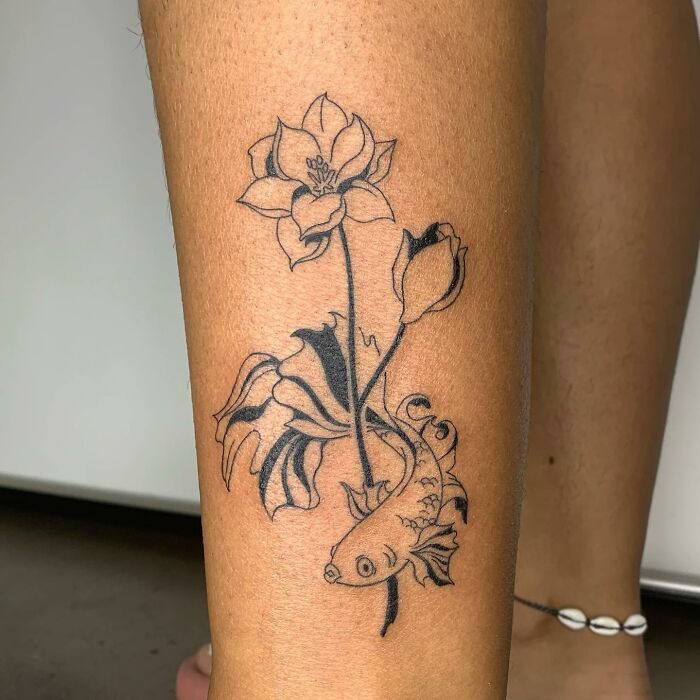 Illustrative tattoo of flowers and a fish on a person's leg, showcasing the artist's unique illustrative style.