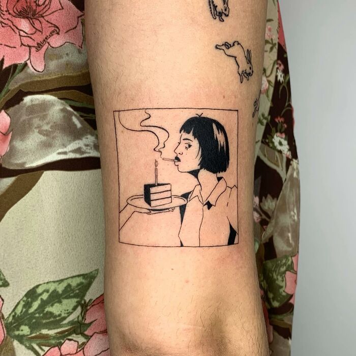Illustration-style tattoo depicting a woman blowing out a candle on a cake.