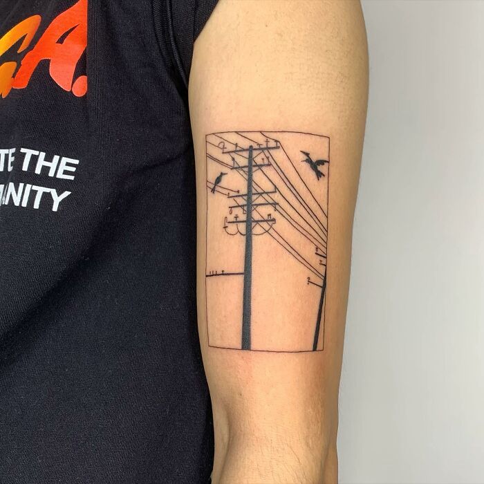 Illustration-style tattoo of power lines and birds on a person's arm.