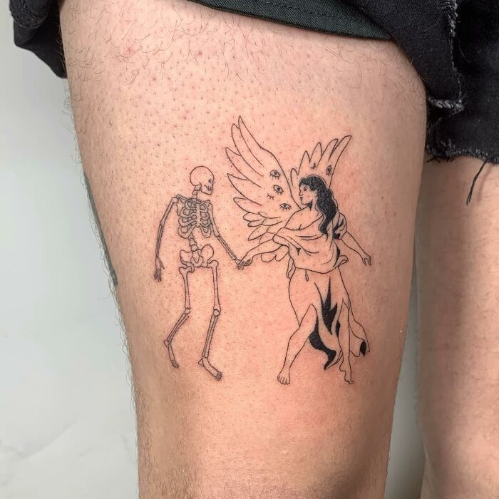Illustrative tattoo of a skeleton and an angel holding hands on a person's thigh.