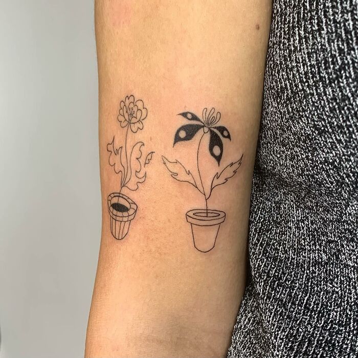 Illustration-style tattoos of plants in pots on skin.