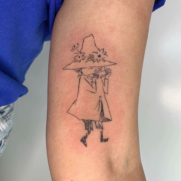 Illustration-style tattoo of a character in a hat and coat on a person's arm, showcasing artist's skill.