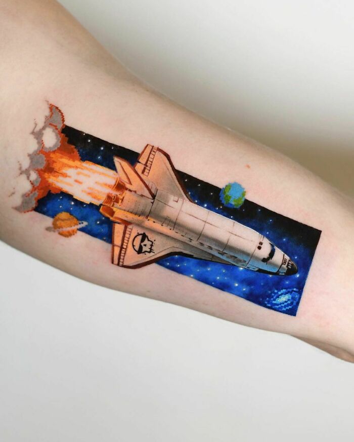 Space tattoo featuring a spaceship with colorful planets in the background.