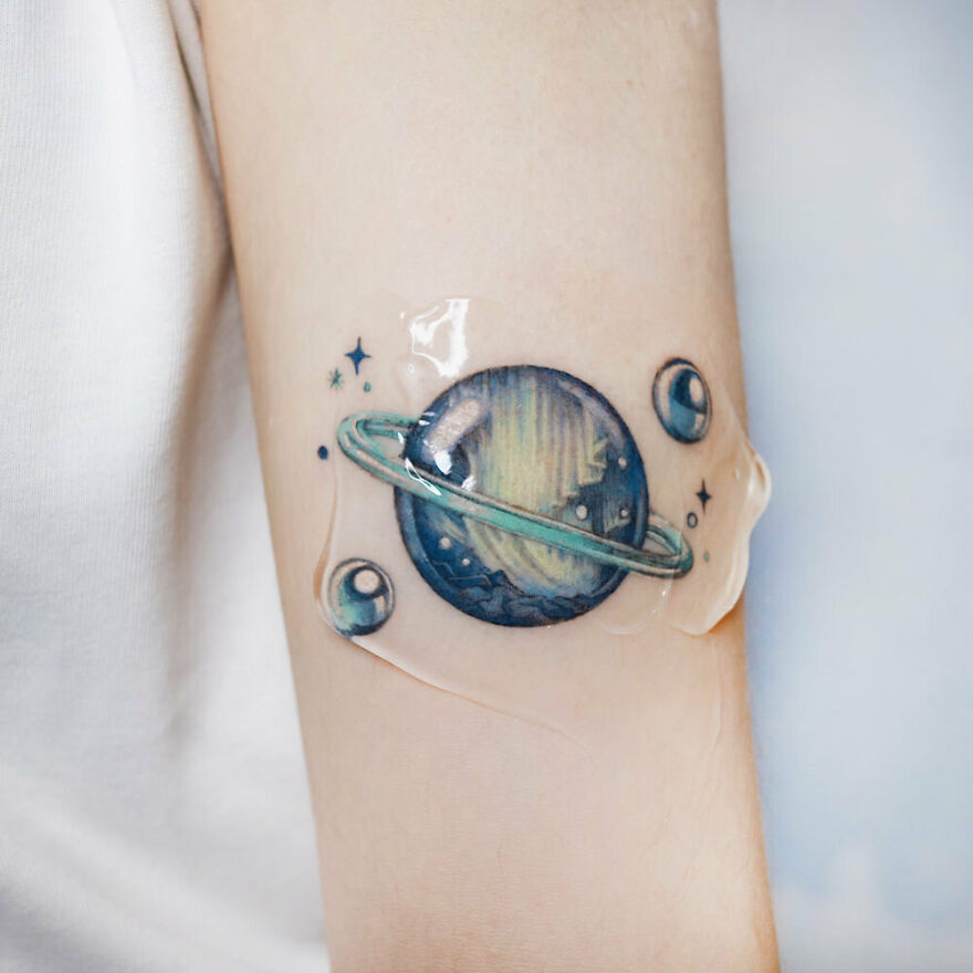 Space tattoo featuring a colorful planet with rings and stars, symbolizing the allure of outer space.