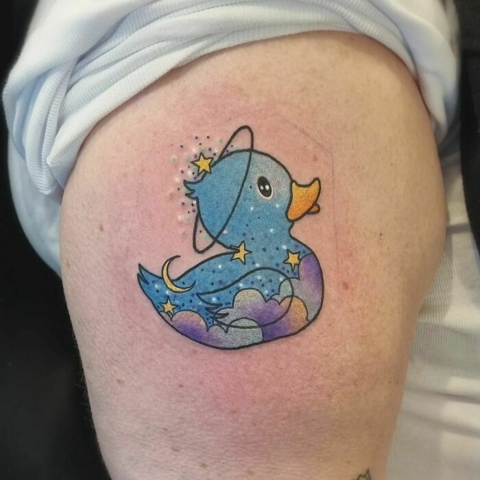 Cute space-themed tattoo of a rubber duck with celestial elements for astrology fans.