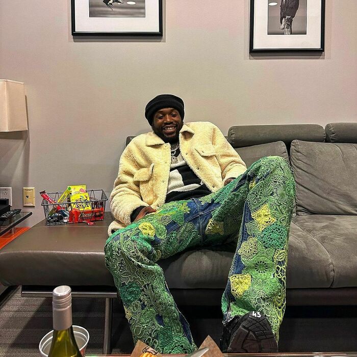 Celebrity in a cozy setting, wearing a beige jacket and colorful pants, associated with minor and severe crimes.