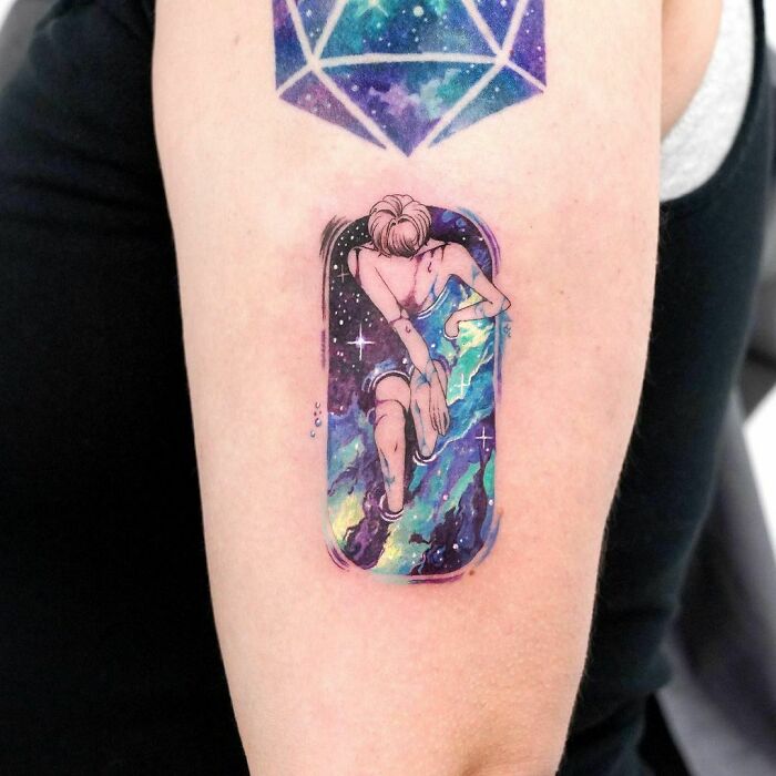 Space tattoo featuring a cosmic figure and geometric galaxy design on an arm.