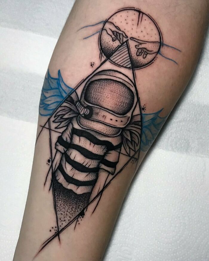 Space tattoo featuring an astronaut with geometric designs on an arm.