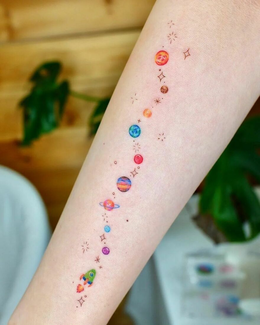 Colorful outer space tattoo on an arm with planets and stars.