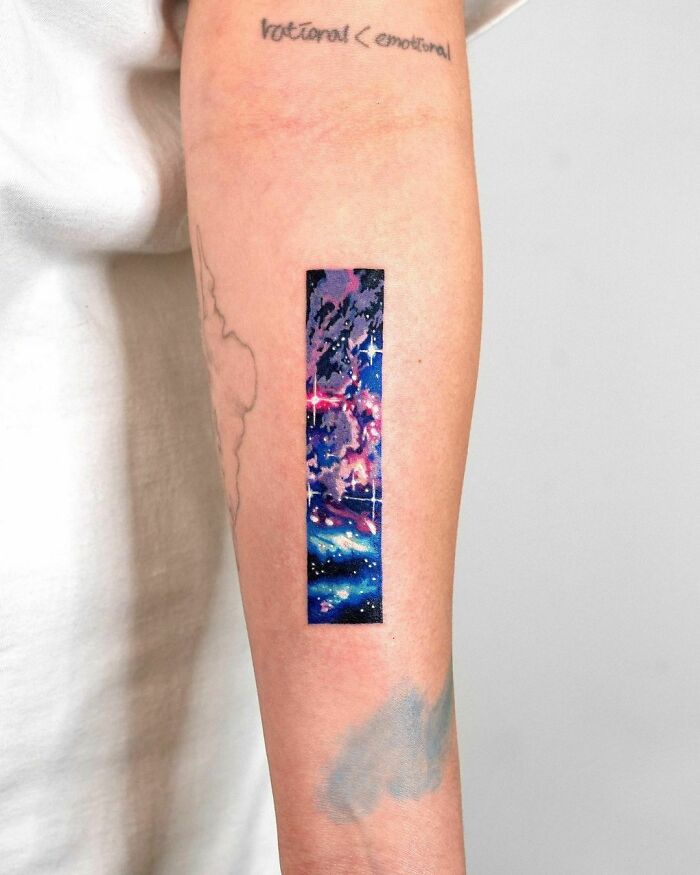 Colorful space tattoo with galaxy on inner forearm.