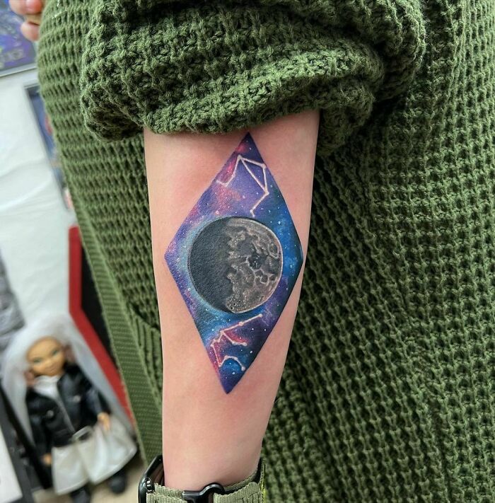 Forearm tattoo of a moon and stars in a colorful space-themed design, perfect for astrology fans.
