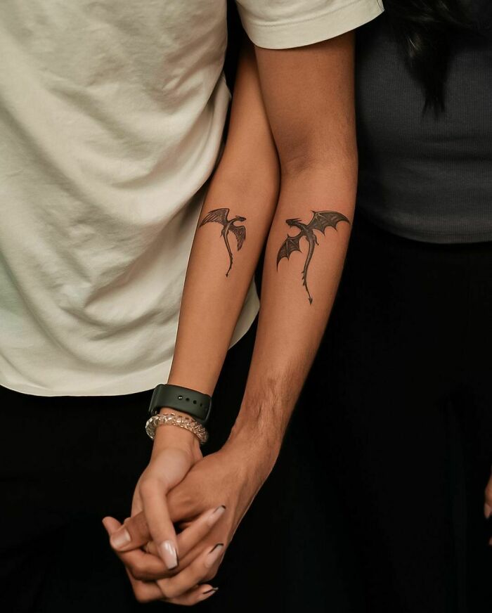 Matching tattoos of dragons on couple's forearms, symbolizing connection and unity.