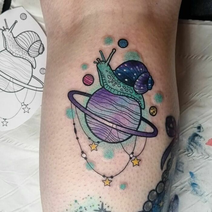 Colorful space tattoo featuring a snail on a planet with rings and stars, perfect for astrology fans.