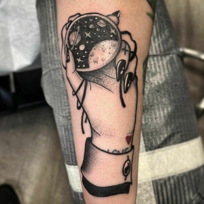 Arm tattoo featuring a hand holding a celestial sphere, perfect for astrology fans.