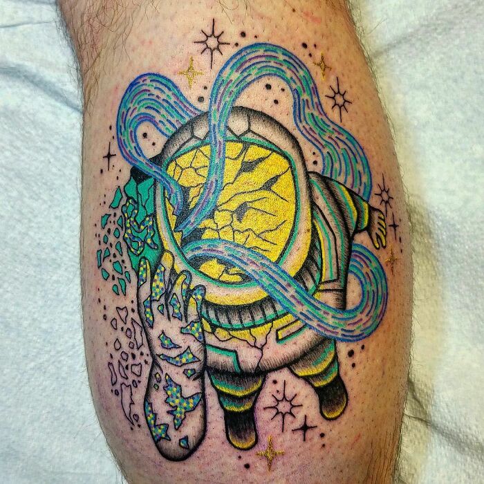 Colorful space tattoo of an astronaut with cosmic elements on a person's leg.