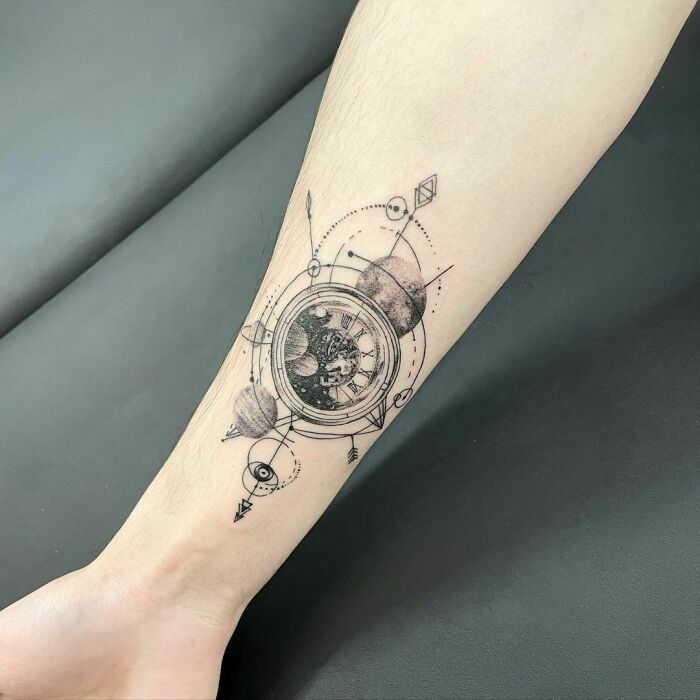 Astrology-themed space tattoo on forearm, featuring planets and geometric designs.