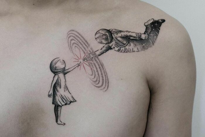 Space tattoo depicting an astronaut and child connecting through a cosmic swirl on a person's shoulder.