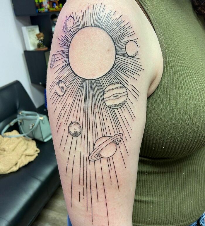 Space tattoo featuring planets and the sun on a person's arm, showcasing cosmic design elements.