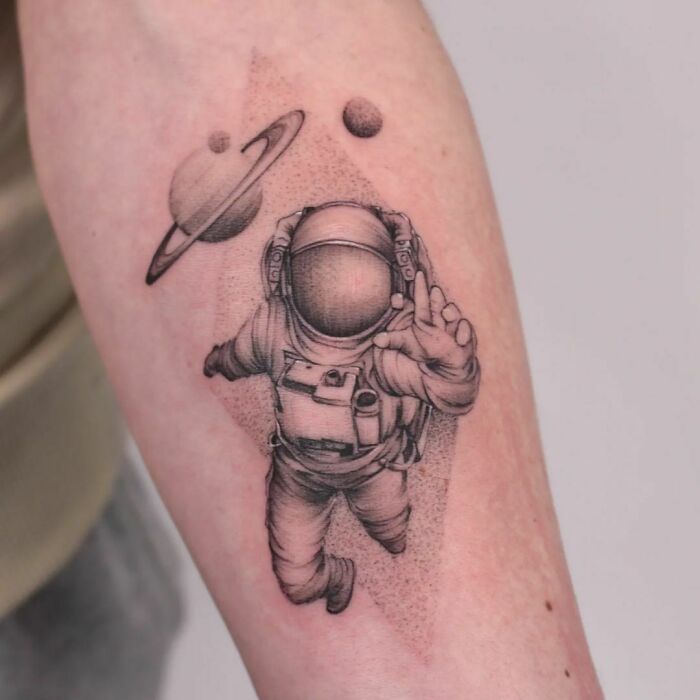 Astronaut tattoo with planets on forearm, perfect for astrology fans.