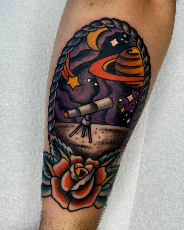 Colorful space tattoo featuring a telescope, planets, and stars above a rose.