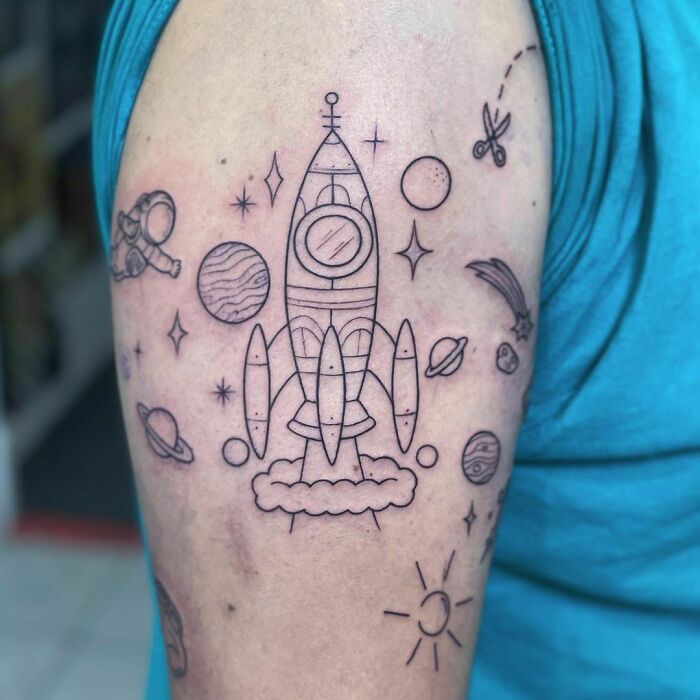 Rocket space tattoo with planets and stars on upper arm for astrology fans.