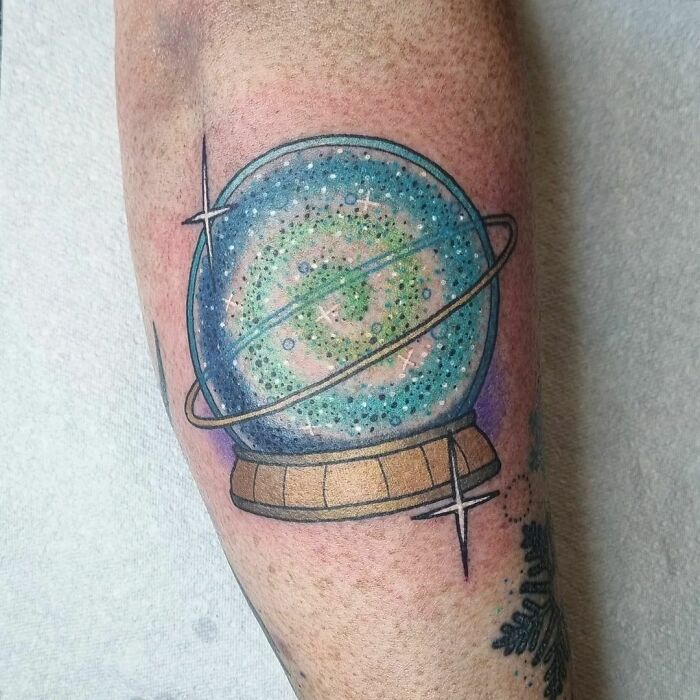 Colorful galaxy tattoo with Saturn rings on forearm for astrology fans.