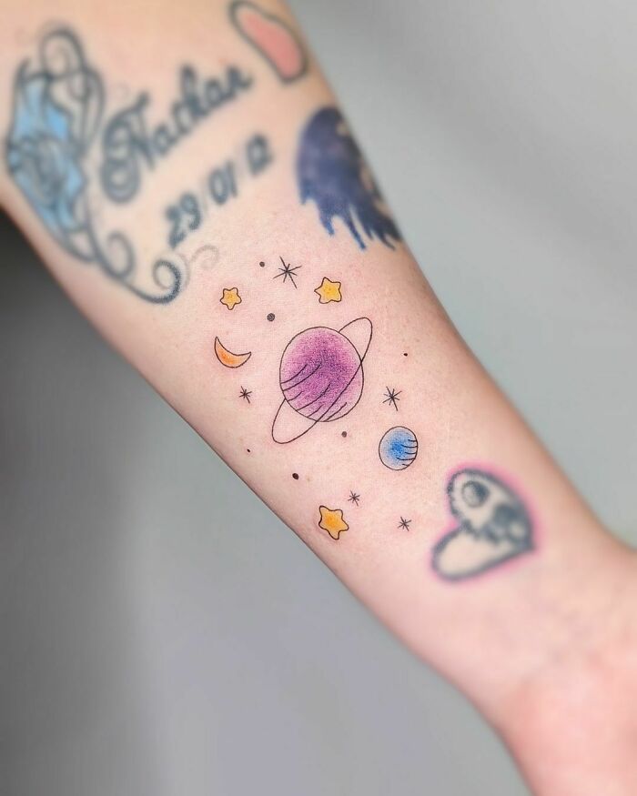 Colorful space tattoo with planets and stars on a forearm, perfect for astrology fans.