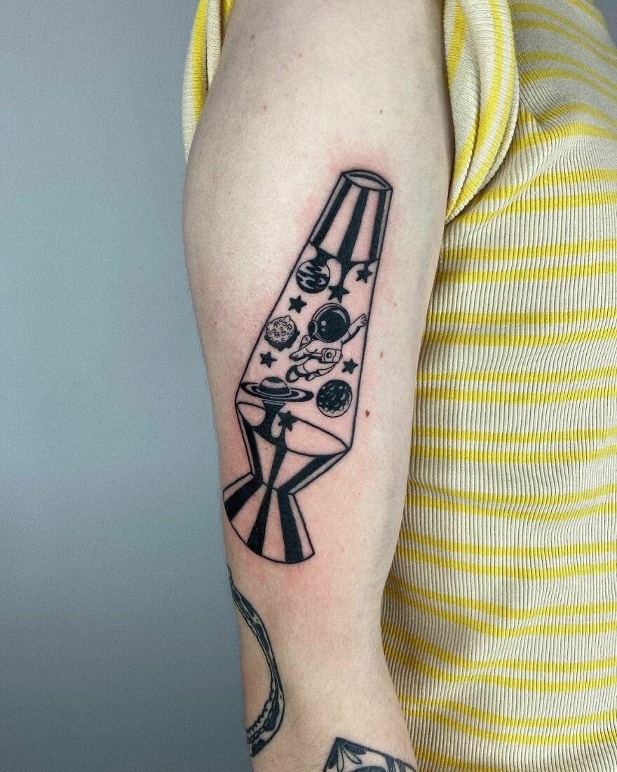 Space tattoo of a lava lamp design featuring planets and an astronaut on an arm in a striped yellow shirt.
