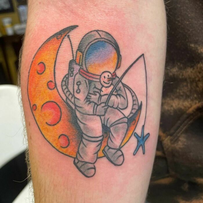 Astronaut sitting on a crescent moon, fishing for a star, a perfect space tattoo for astrology fans.