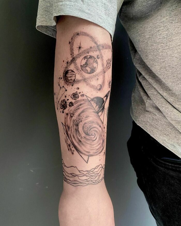 Space tattoo with planets and galaxies on a person's arm, showcasing intricate astrology-themed artwork.