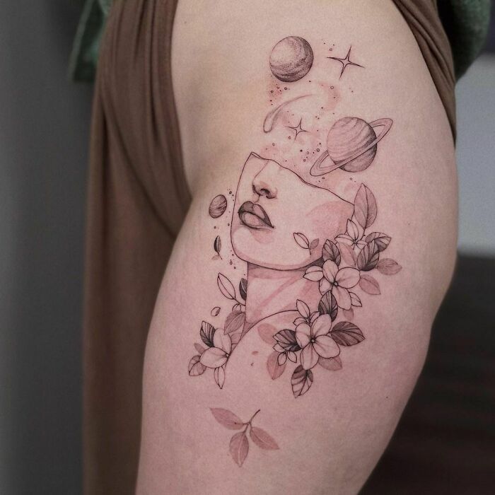 Space tattoo featuring a woman's face with planets and flowers, designed with cosmic elements.