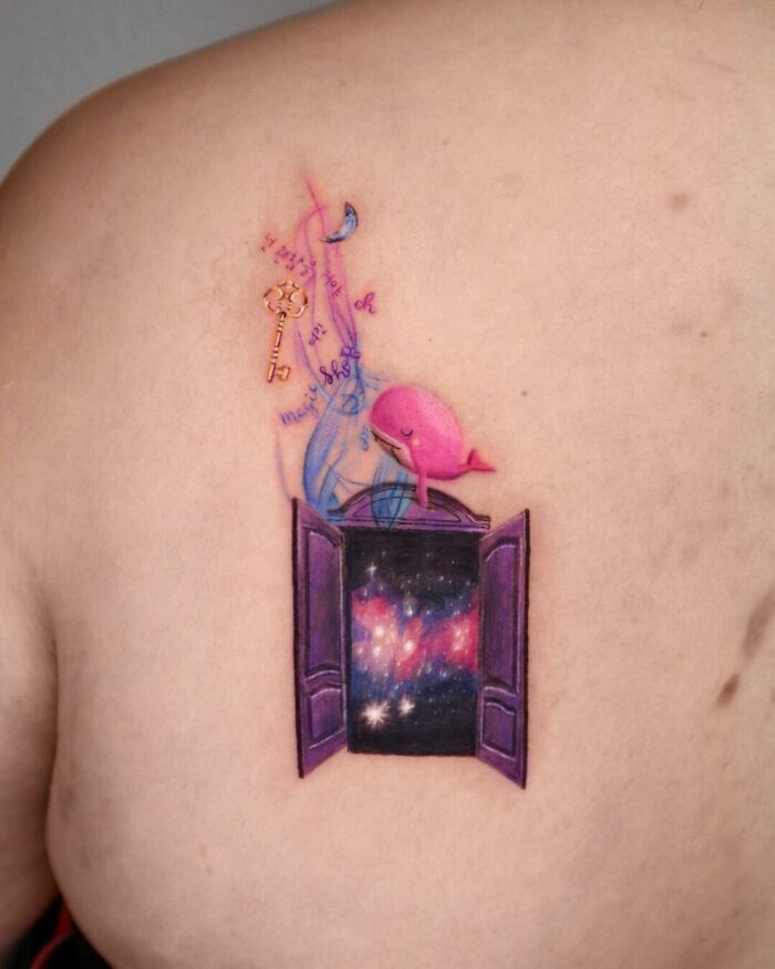 Space tattoo featuring a window to the galaxy with a pink whale and cosmic elements on a person's back.