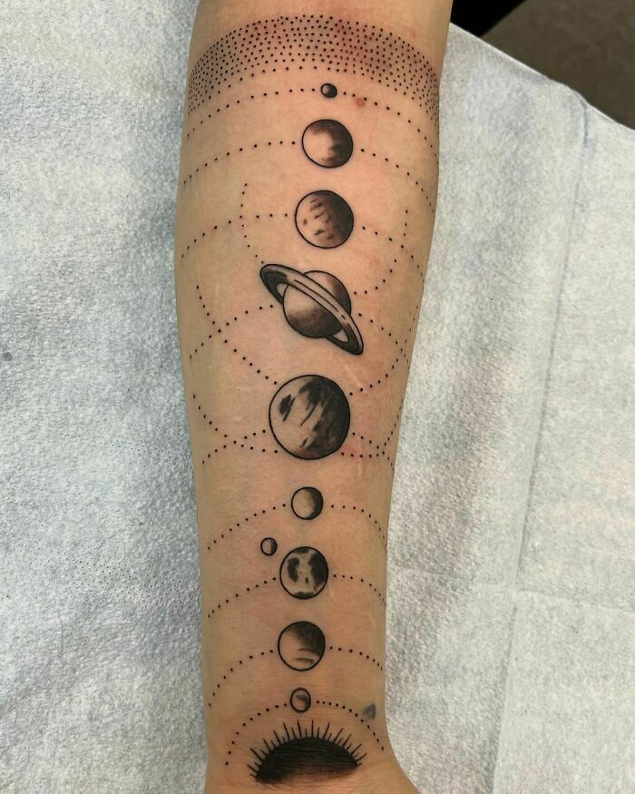 Space tattoo featuring planets and celestial designs on a forearm.